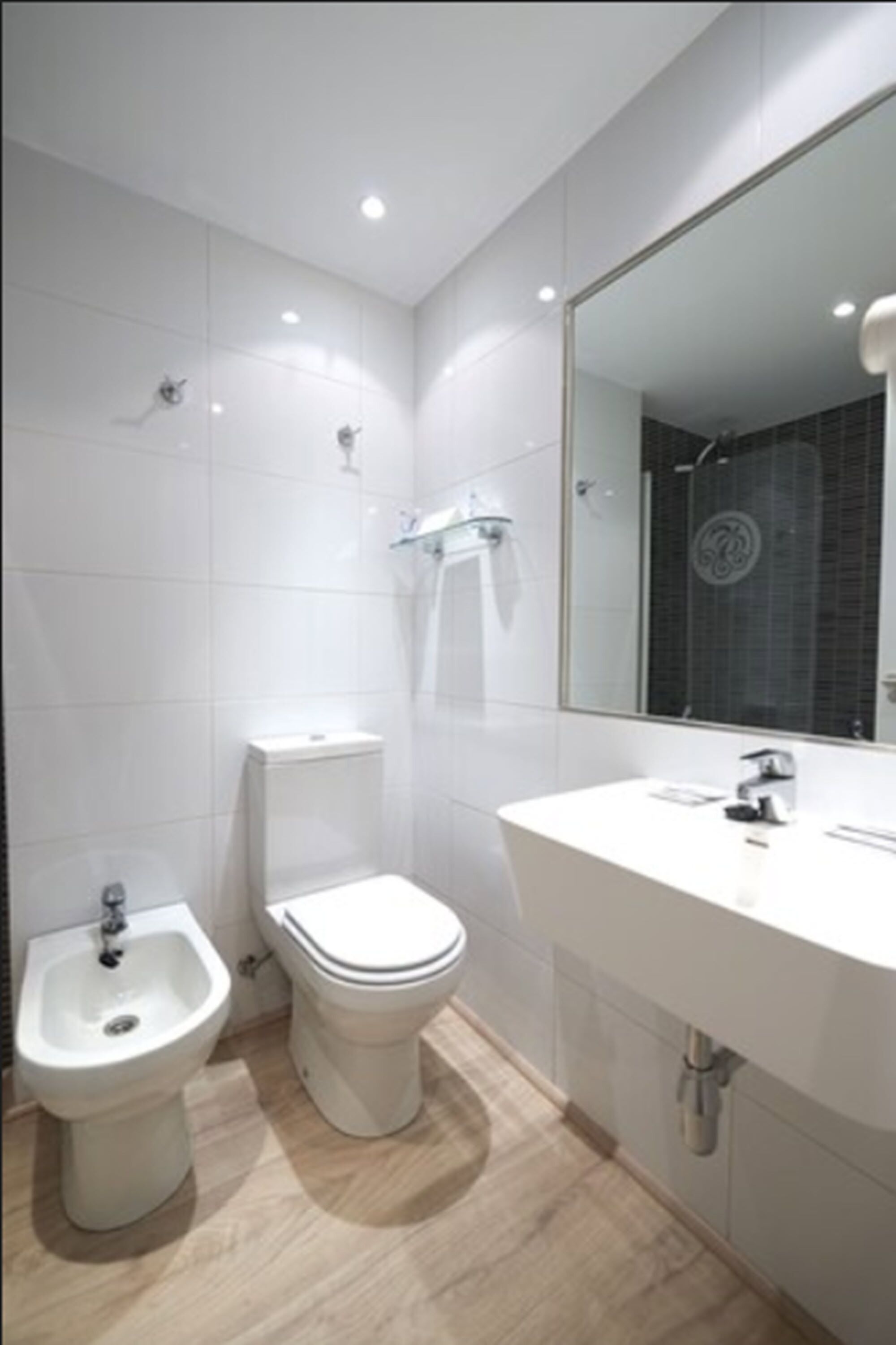 Un baño moderno con bidé, inodoro y lavamanos.
