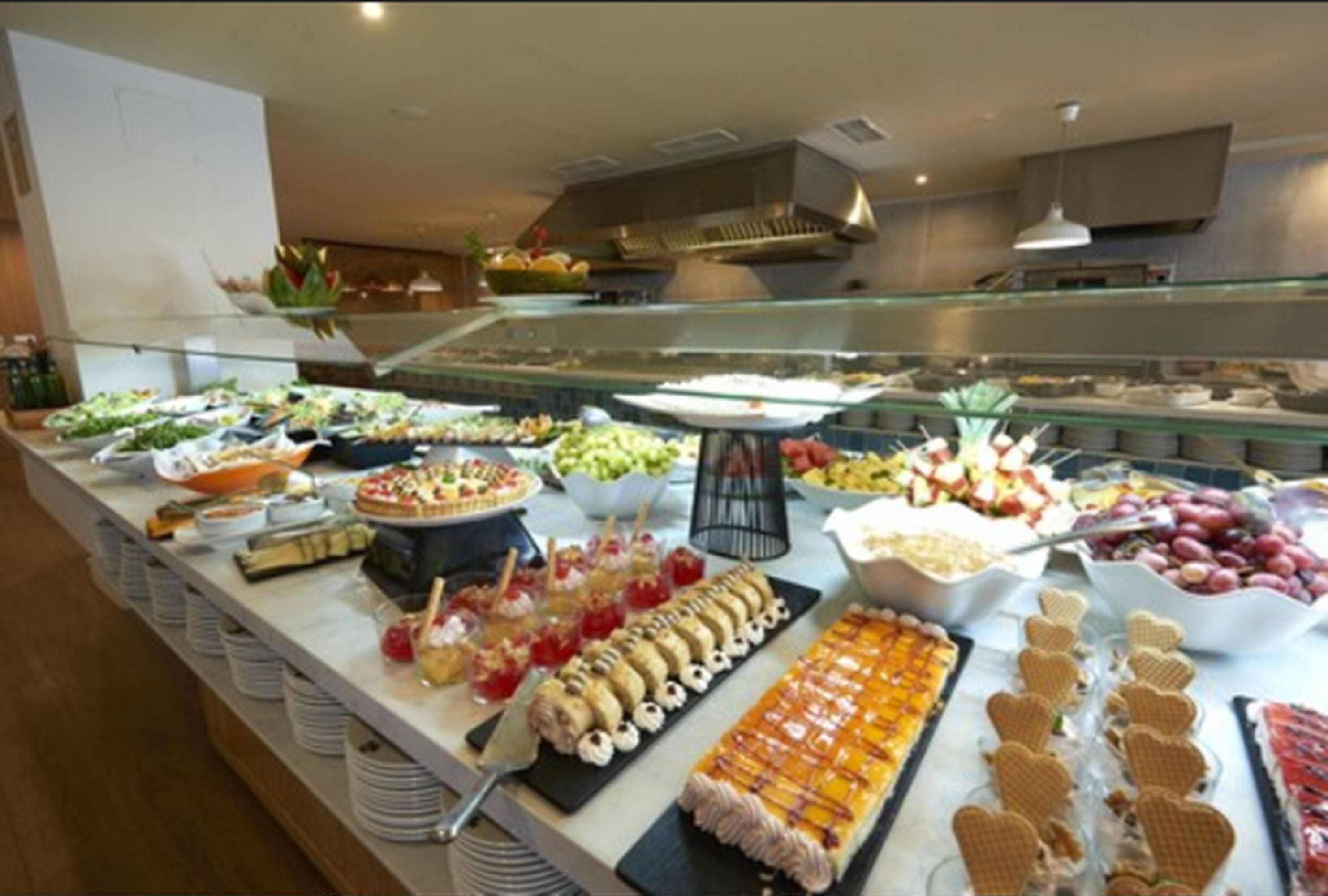 A buffet with a variety of food items including fruits, desserts, and snacks.