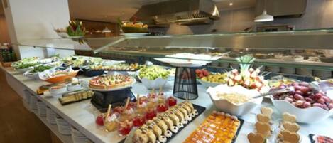 A buffet with a variety of food items including fruits, desserts, and snacks.