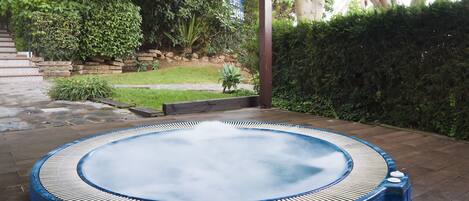 A hot tub in a garden with a stone staircase and lush greenery.