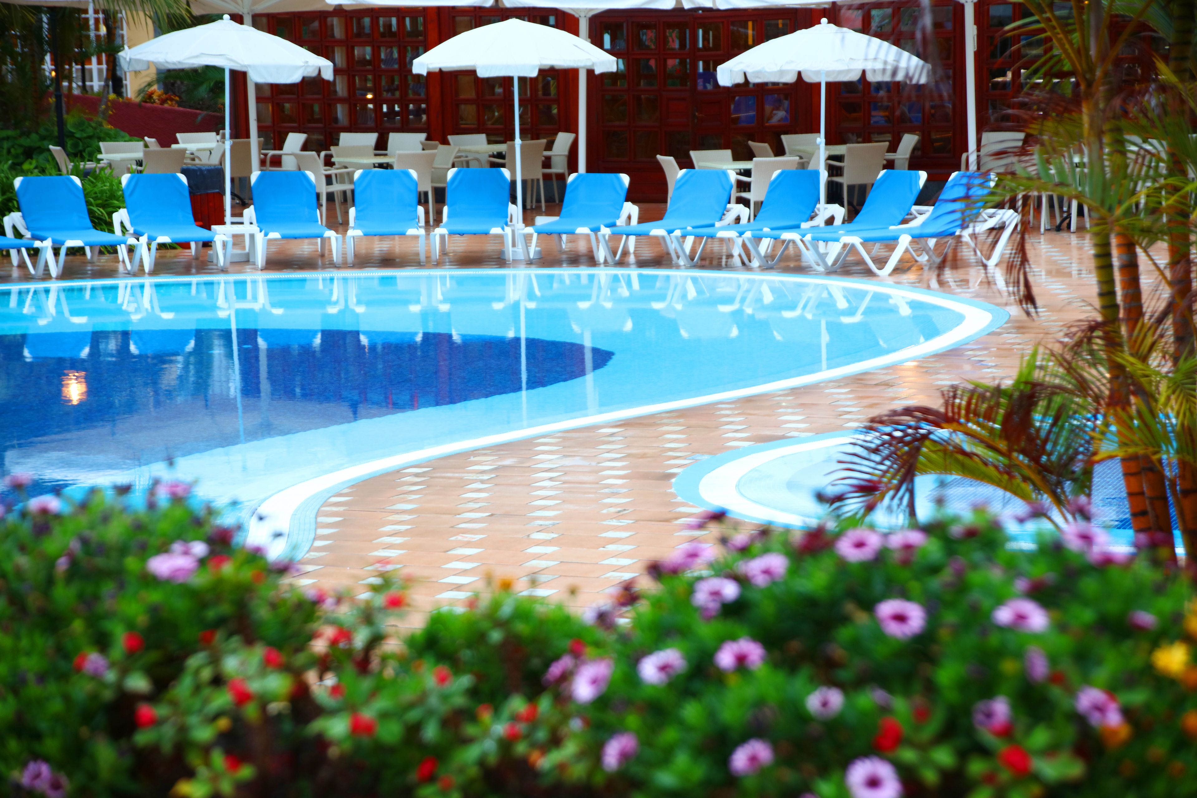A pool area with blue lounge chairs and white umbrellas.