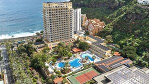 Un resort con un gran edificio, piscina y cancha de tenis.