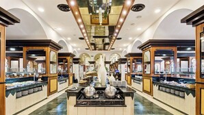 Zona de bufé con varias estaciones de comida, un mostrador central de servicio y un diseño moderno de techo con iluminación empotrada.