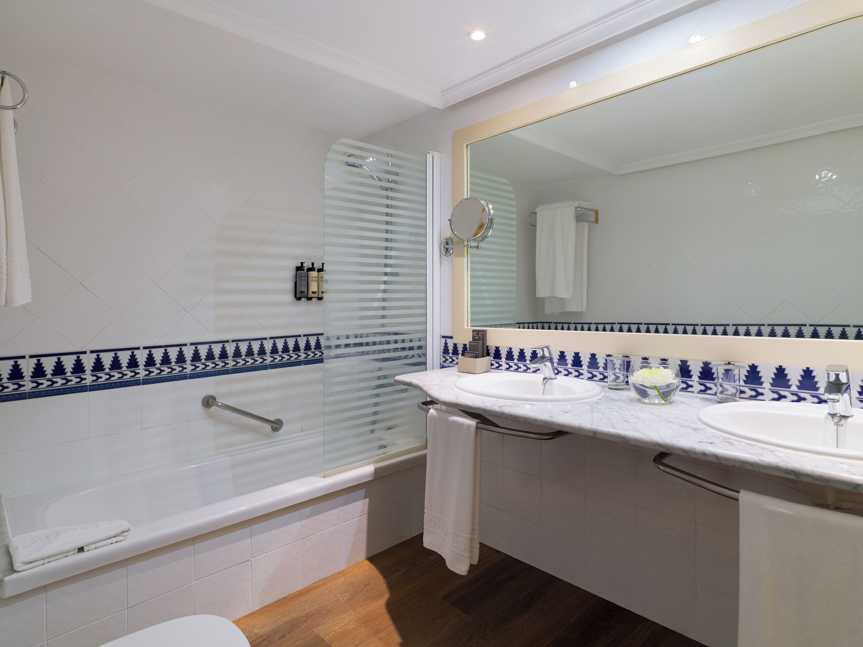 Un baño con bañera, dos lavabos, un espejo grande y una ducha con puerta de vidrio.