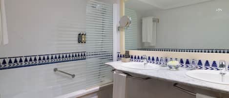 A bathroom with a bathtub, two sinks, a large mirror, and a shower with a glass door.