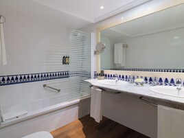 Un baño con bañera, dos lavabos, un espejo grande y una ducha con puerta de vidrio.