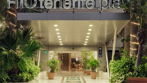 Entrada de un hotel con un cartel que dice "H1oterife Plaza".