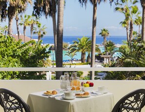 Una mesa lista para el desayuno con vista al océano y palmeras.