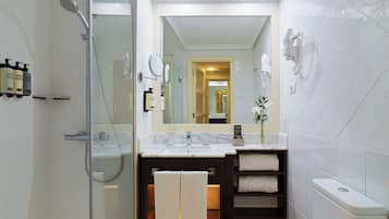 A modern bathroom with a glass shower enclosure, a vanity with a mirror, and a toilet.