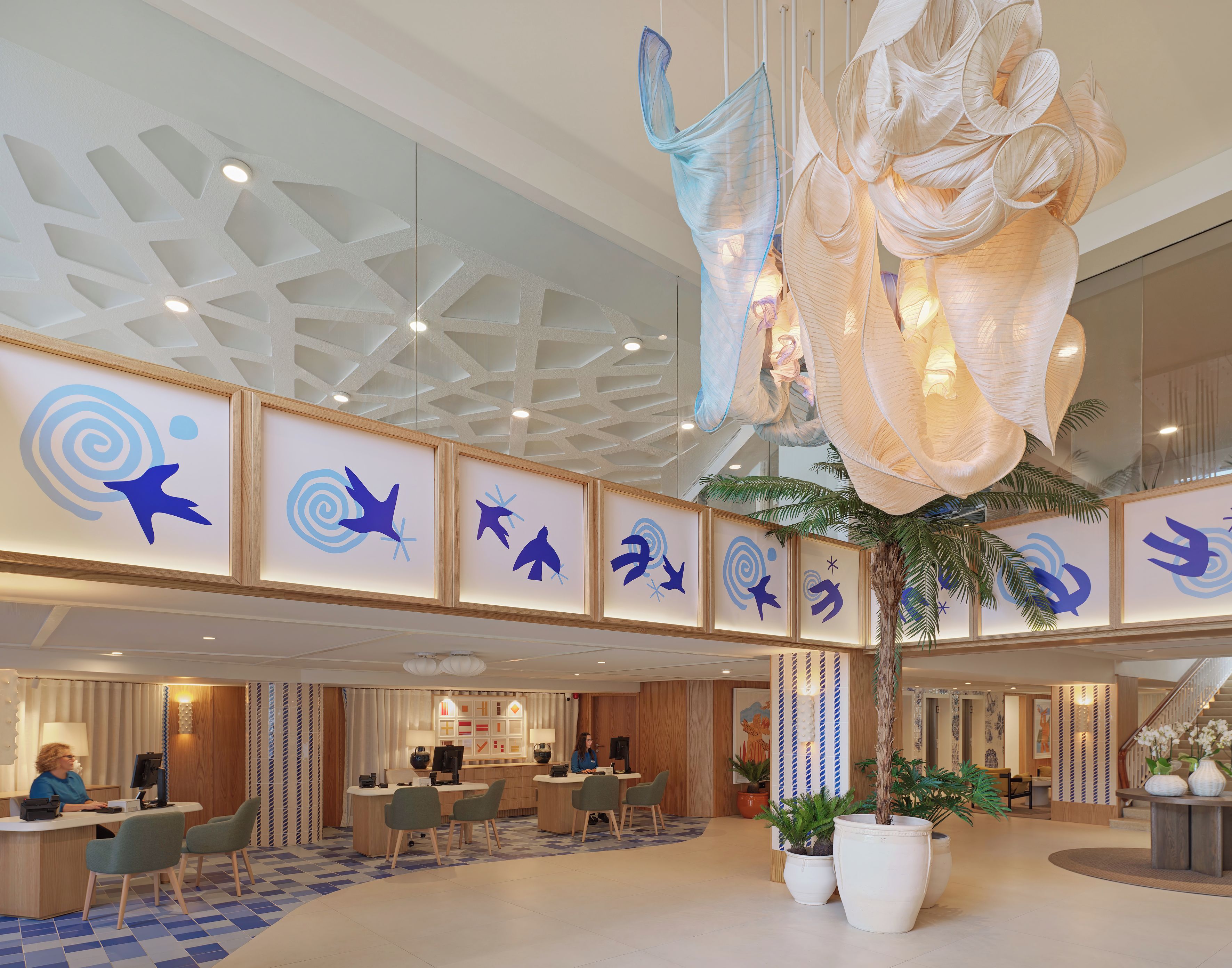 A hotel lobby with a reception desk, seating area, and decorative ceiling.