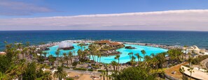 Un resort con piscina central, palmeras y vistas al océano.