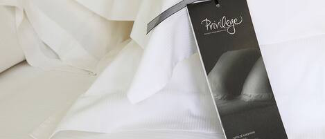 A black tag with the word "Privilege" and "Exclusive Bedding and Services" on a white bedspread.