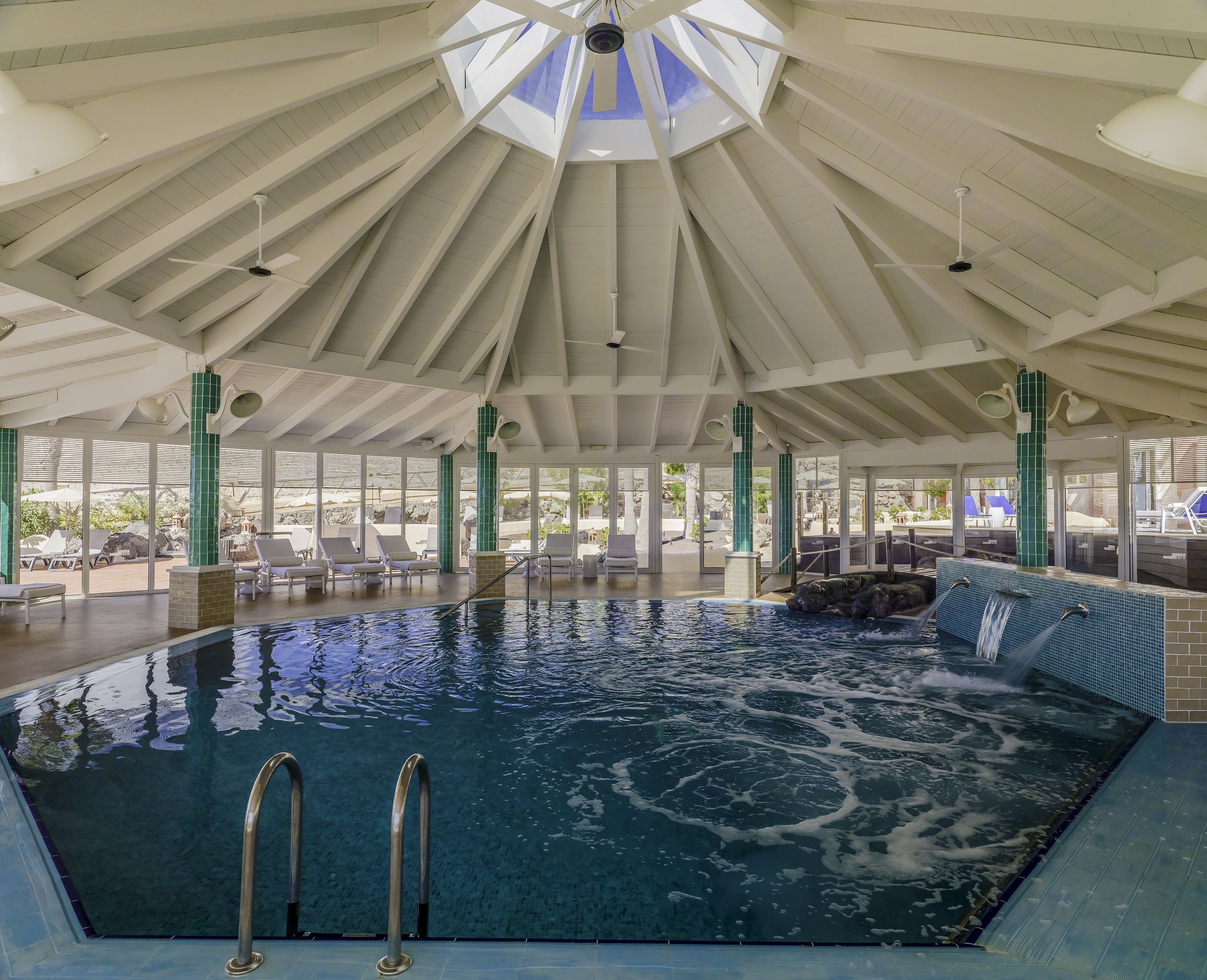 A large indoor swimming pool with a high ceiling and multiple levels of seating around the perimeter.