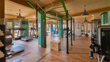 A gym with treadmills, weight machines, and a wooden floor.