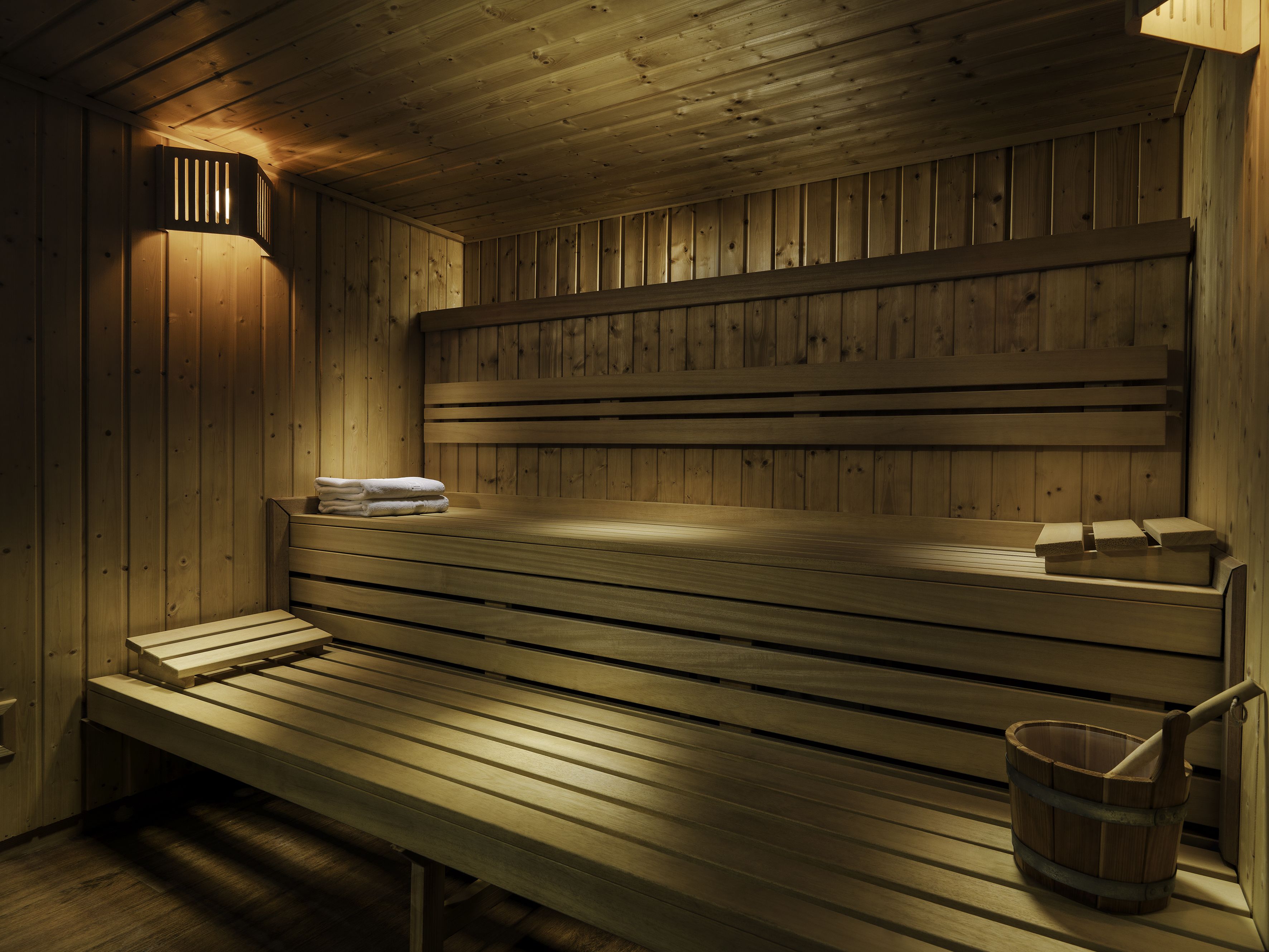 A wooden sauna with benches and a bucket.