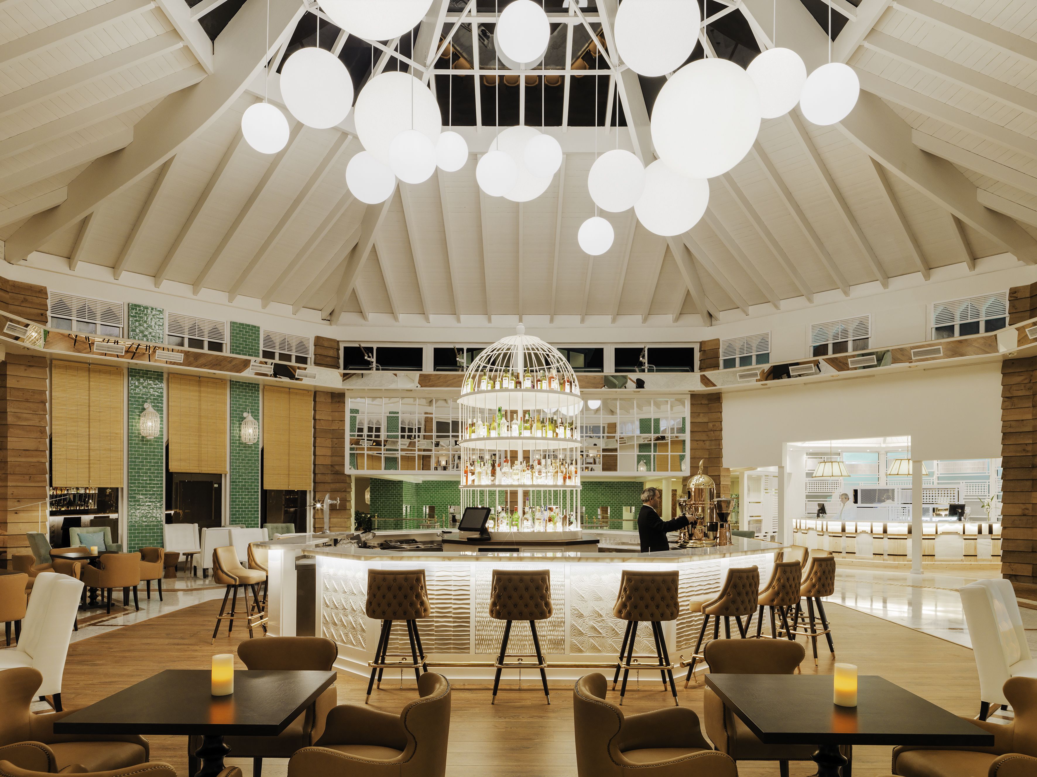 A spacious hotel lobby with a high ceiling, a central bar area, and multiple seating arrangements.