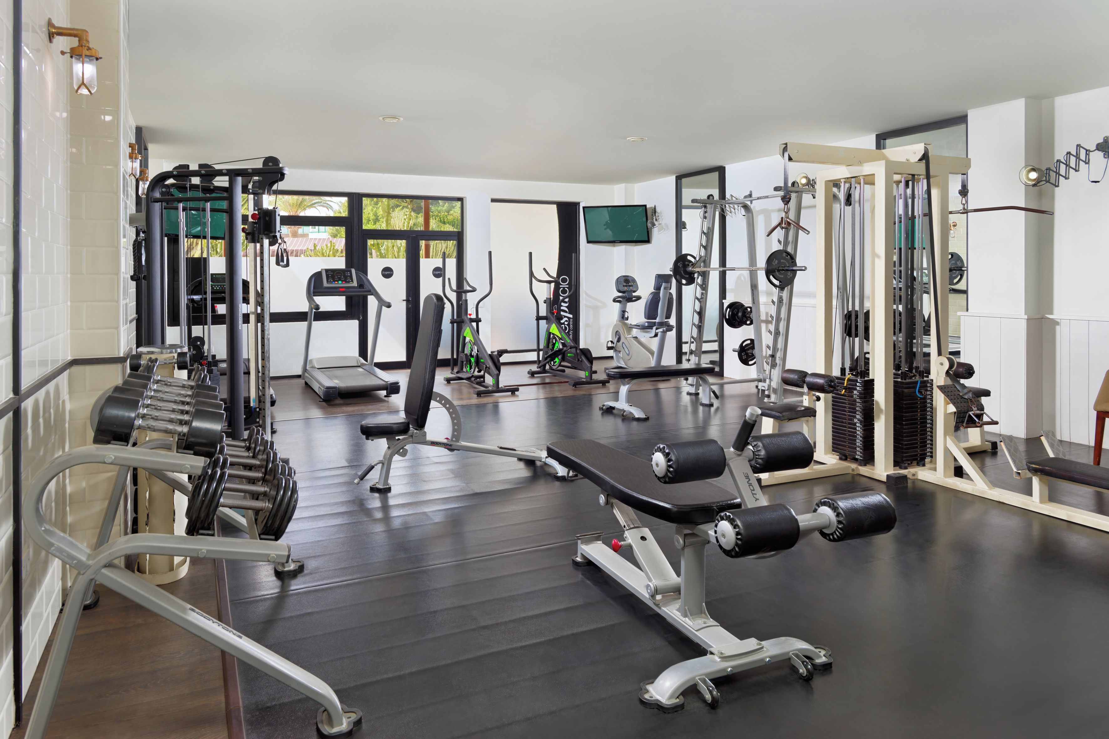 Une salle de sport équipée de divers appareils d’exercice, notamment des tapis de course, des appareils de musculation et des poids libres.