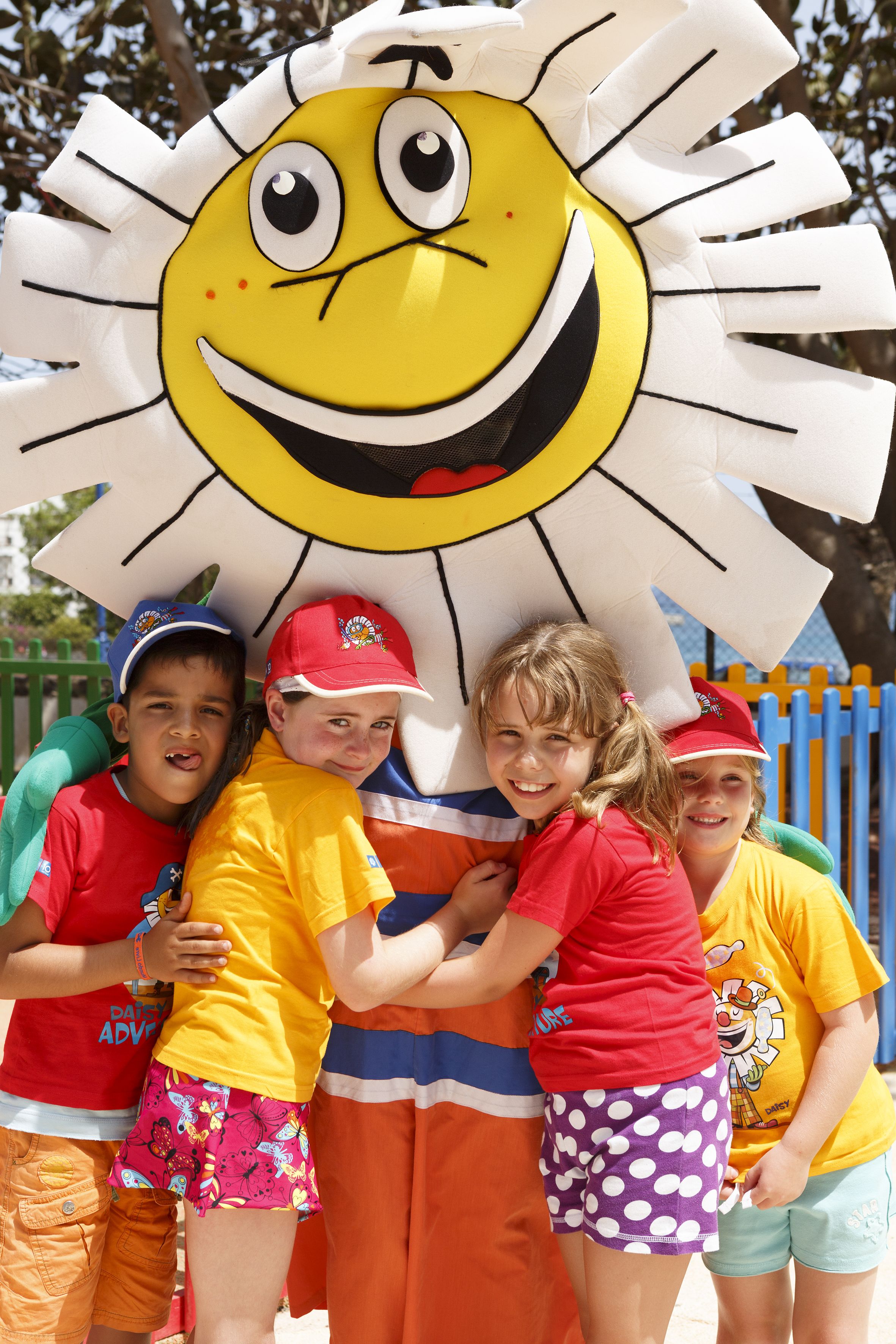 Un grupo de niños de pie frente a un adorno grande con forma de sol.