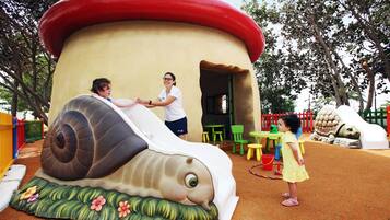 Un parque infantil con un tobogán en forma de caracol y una casita también con forma de caracol.