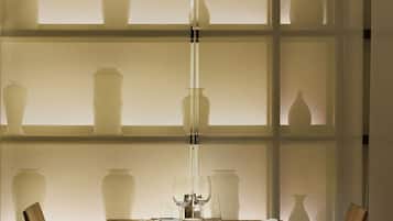 A dining table with chairs, a vase, and a bottle on the table.