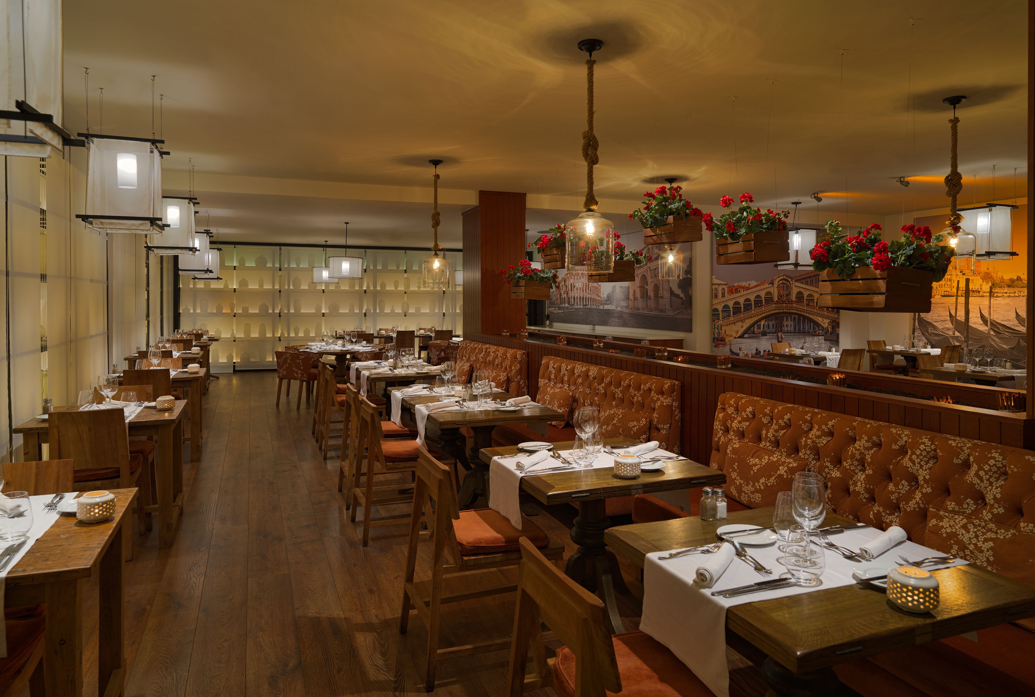 Ein Restaurant mit Holztischen und -stühlen, einer Bar und hängenden Blumenkörben.