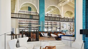 A spacious lobby with a high ceiling, large arched windows, and a central seating area with modern chairs and a coffee table. - H10 Timanfaya Palace (Yaiza)