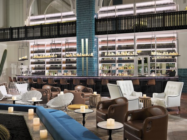 A bar area with multiple seating options, including chairs and sofas, and a large wine and liquor display. - H10 Timanfaya Palace (Yaiza)