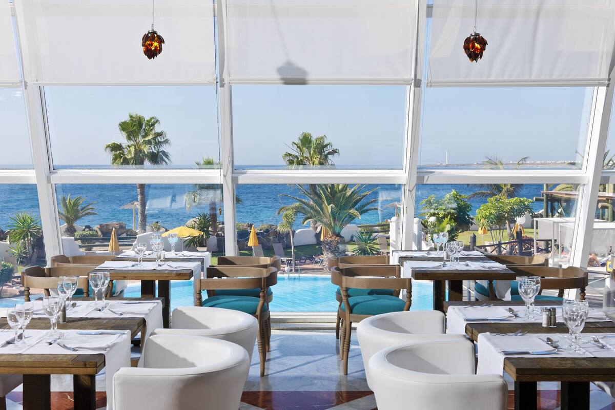 Un ristorante con tavoli e sedie disposti vicino a una piscina, con vista sull'oceano.