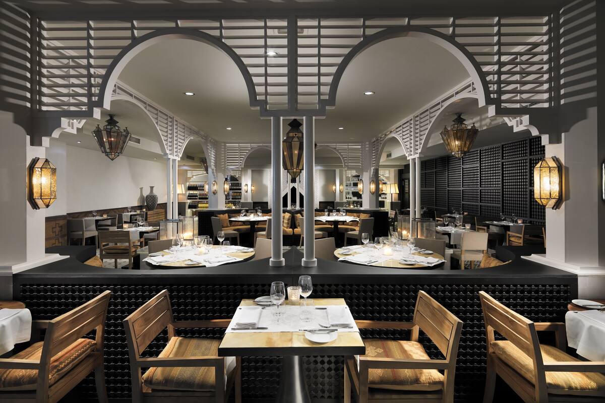 Un ristorante con un bancone centrale, posti a sedere riservati e un soffitto alto con illuminazione decorativa.