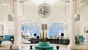 A spacious lobby with a central seating area, a reception desk, and a large decorative chandelier. - H10 Timanfaya Palace (Yaiza)