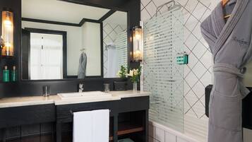 Un baño moderno con un espejo grande, lavamanos dobles, cabina de ducha de vidrio y una bata colgada en un perchero.