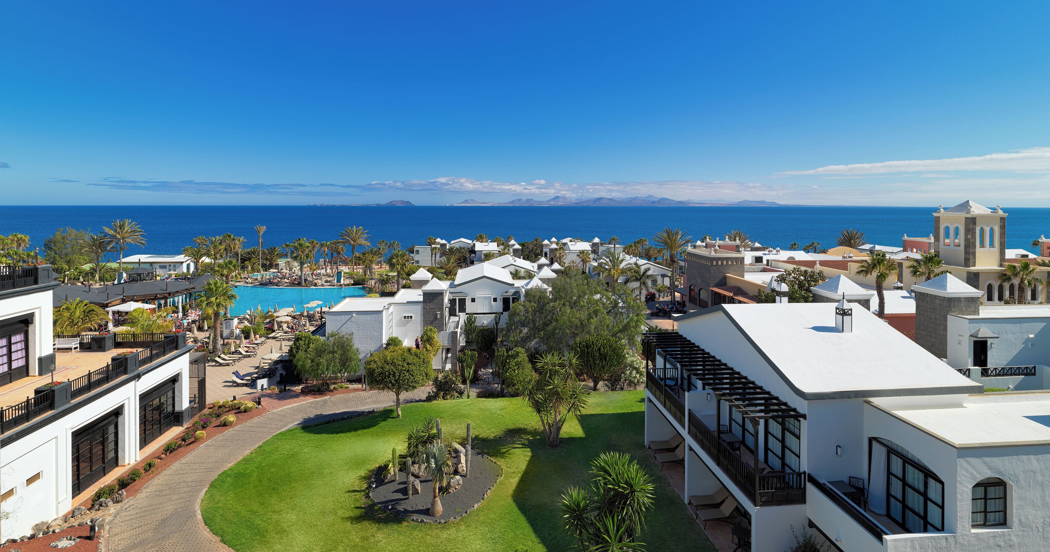 Un resort con piscina, palmeras y vista al mar.