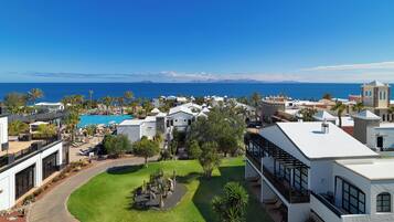 Un resort con piscina, palmeras y vista al mar.