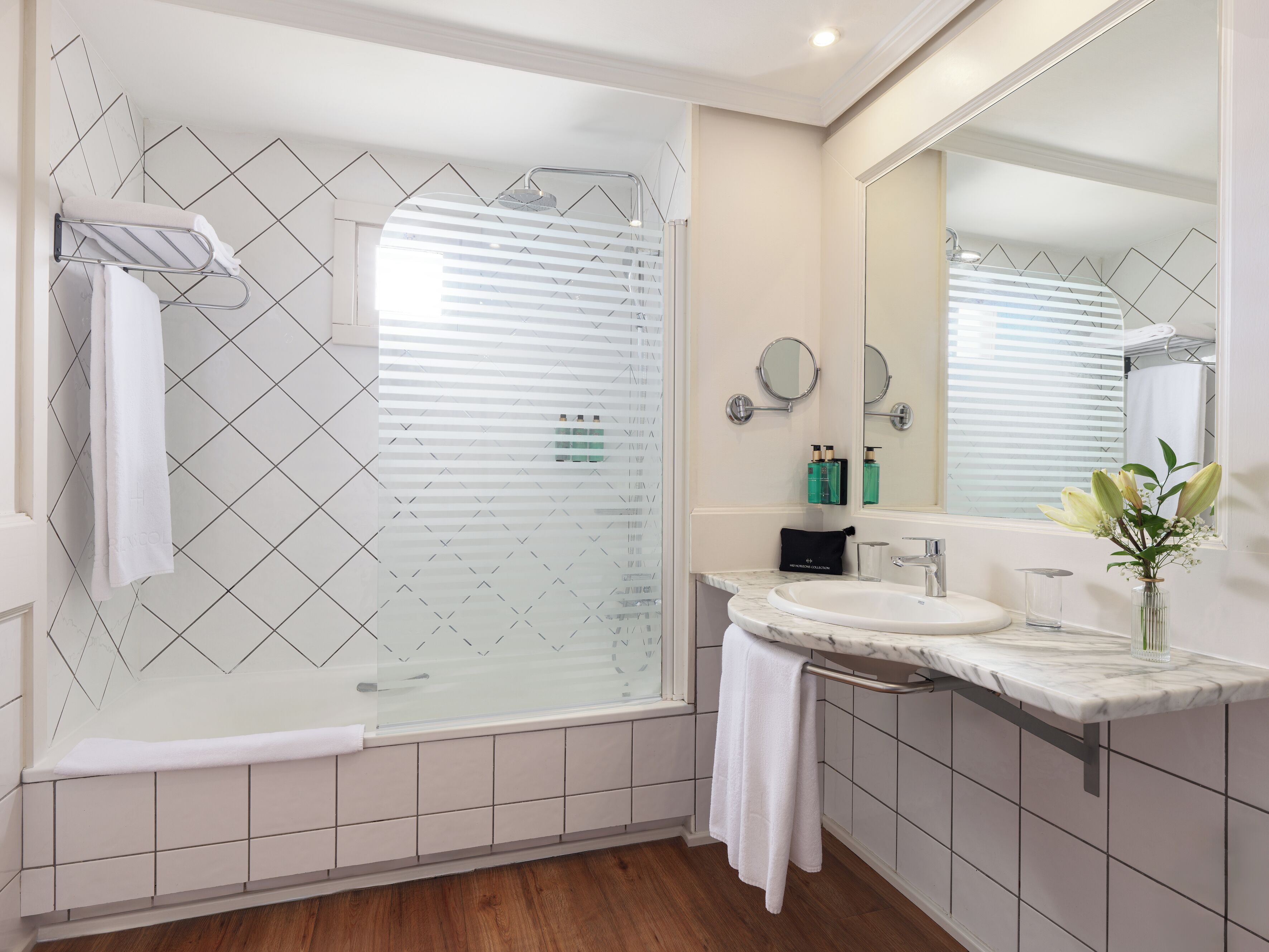 Une salle de bain moderne avec une douche à parois de verre, un lavabo en marbre et un grand miroir.
