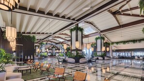 A spacious lobby with a high ceiling, modern furniture, and large windows allowing natural light.