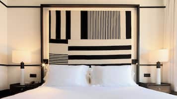 Una habitación de hotel con una cama grande, dos mesitas de noche con lámparas y un cabecero moderno con un diseño geométrico.