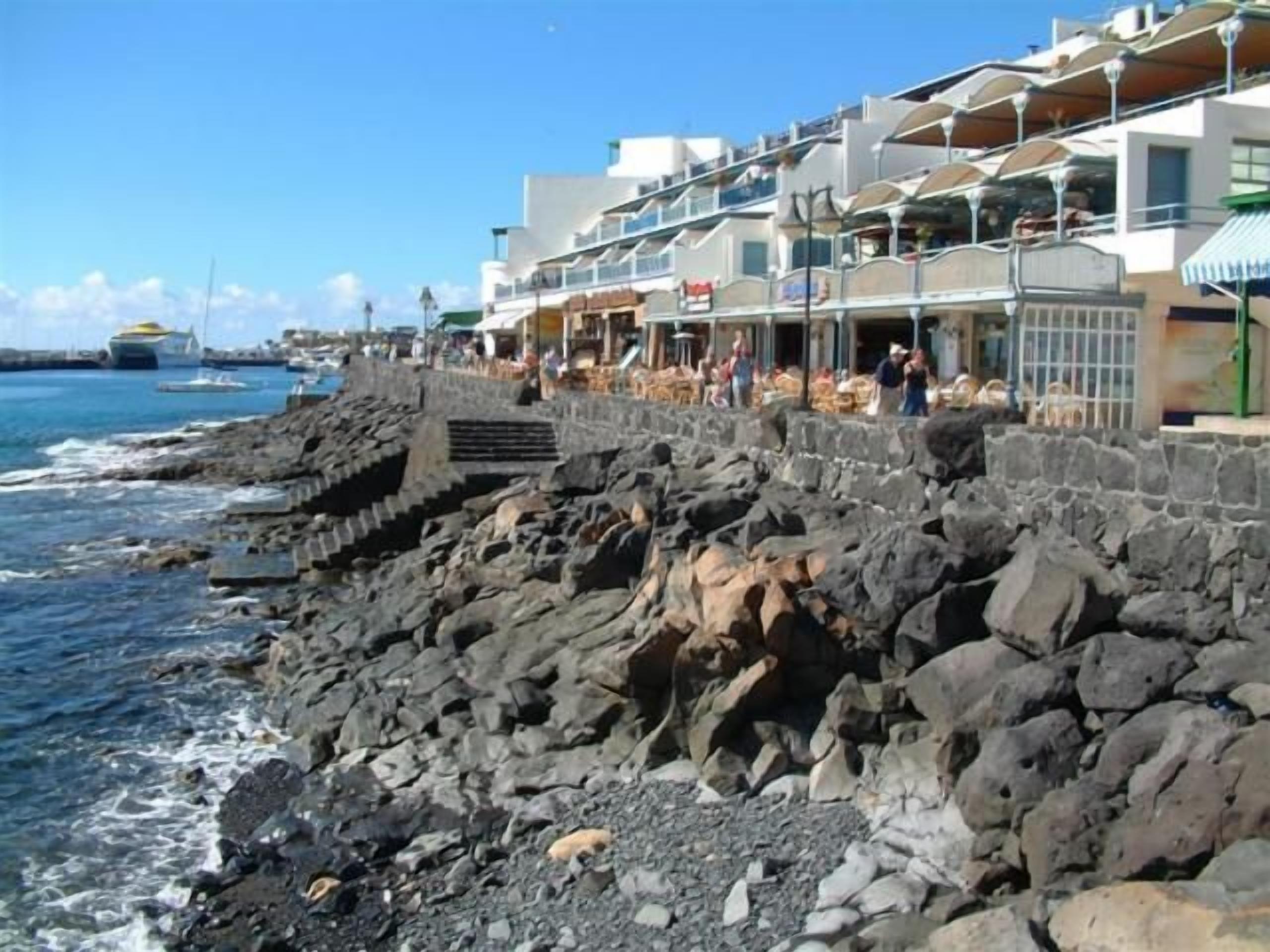 Un hotel frente al mar con costa rocosa, asientos al aire libre y vistas al océano.
