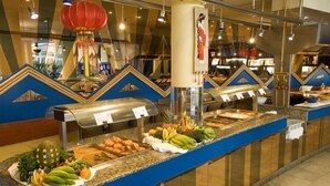 Un comptoir de buffet garni de divers fruits et légumes, une lanterne rouge et un mur décoratif orné de motifs géométriques.