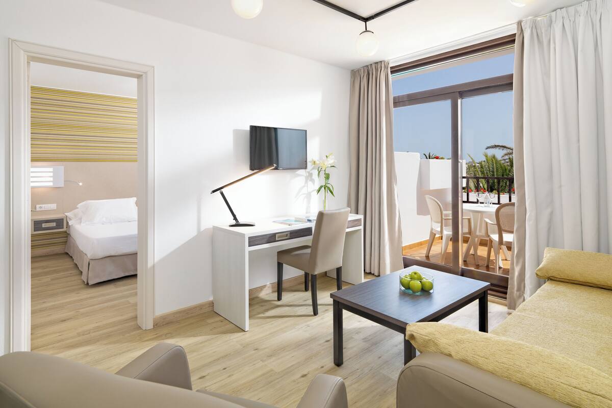 Une chambre d’hôtel moderne avec un lit, un bureau et un balcon.