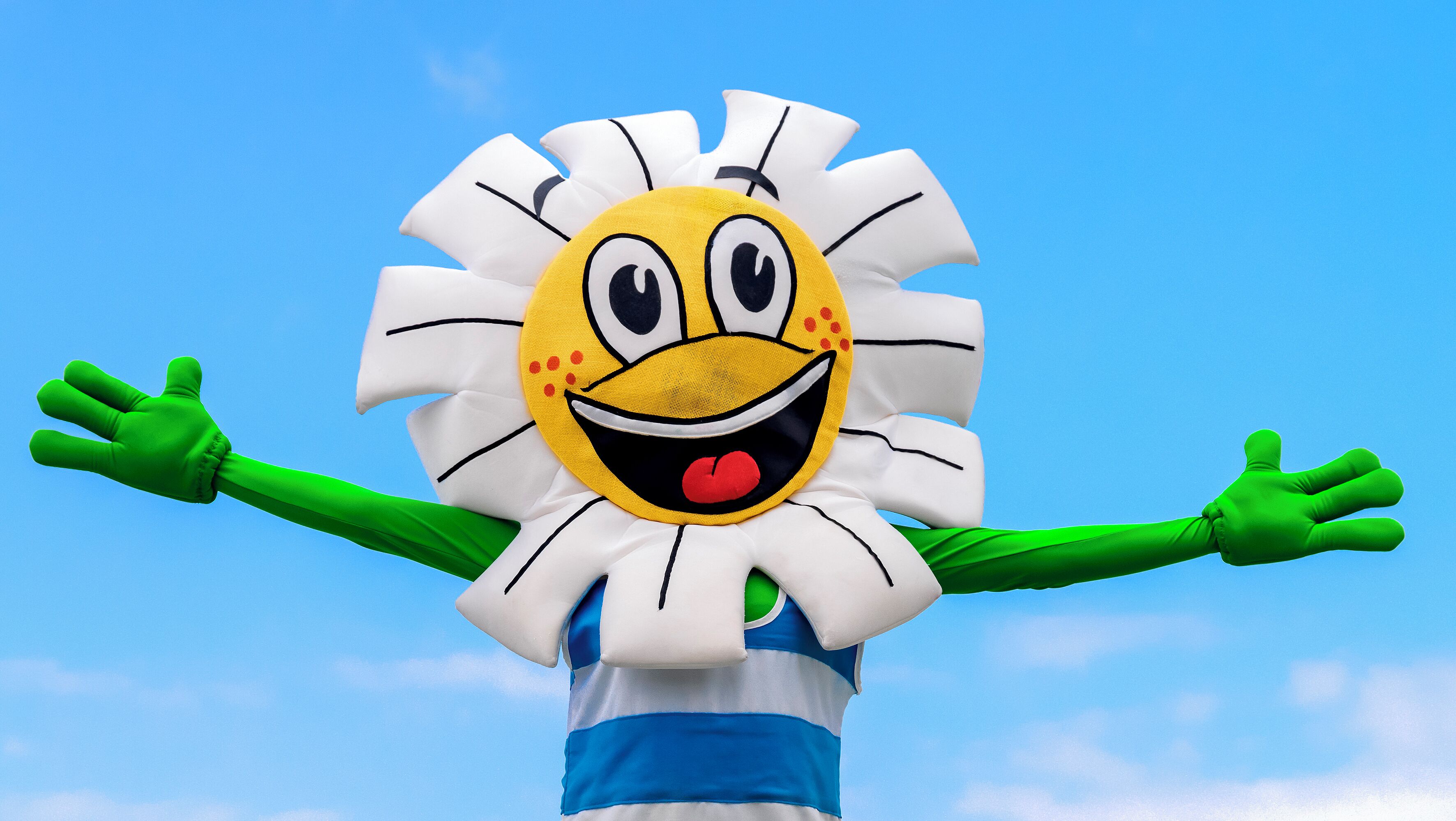 Eine Person in einem Sonnenblumekostüm mit ausgestreckten Armen.