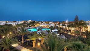 Un resort con piscina, palmeras y vistas al mar.