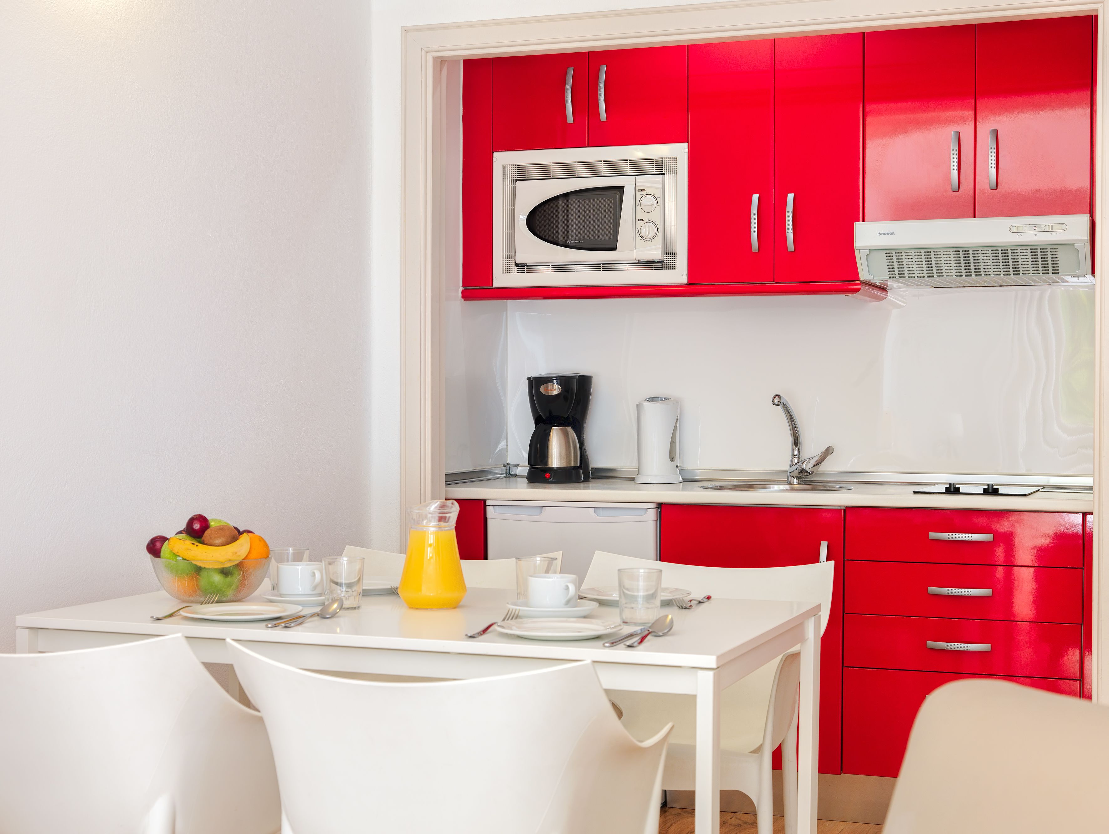 A compact kitchen with a microwave, coffee maker, and a sink.