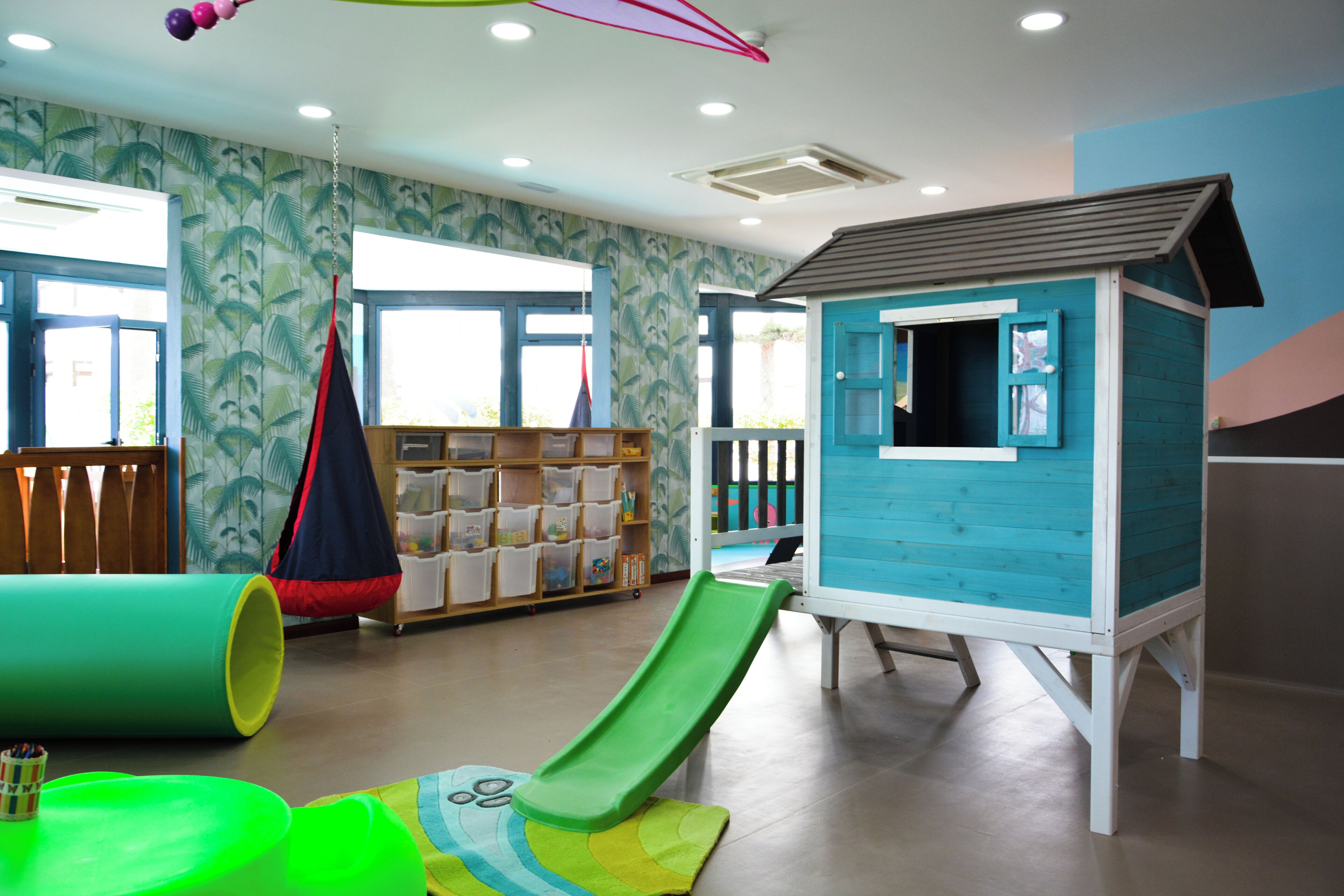 Un área de juegos infantiles con un tobogán, una casita de juegos y estantes para guardar cosas.