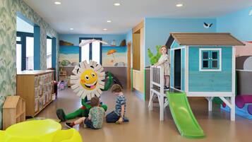 Zona infantil con un tobogán, una casita de juegos y una gran decoración de sol.