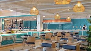 Un restaurante moderno con bufé, varias mesas para comer y lámparas colgantes.