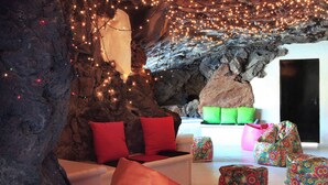 Un interior que recuerda a una cueva, con asientos, luces colgantes y una gran formación rocosa.