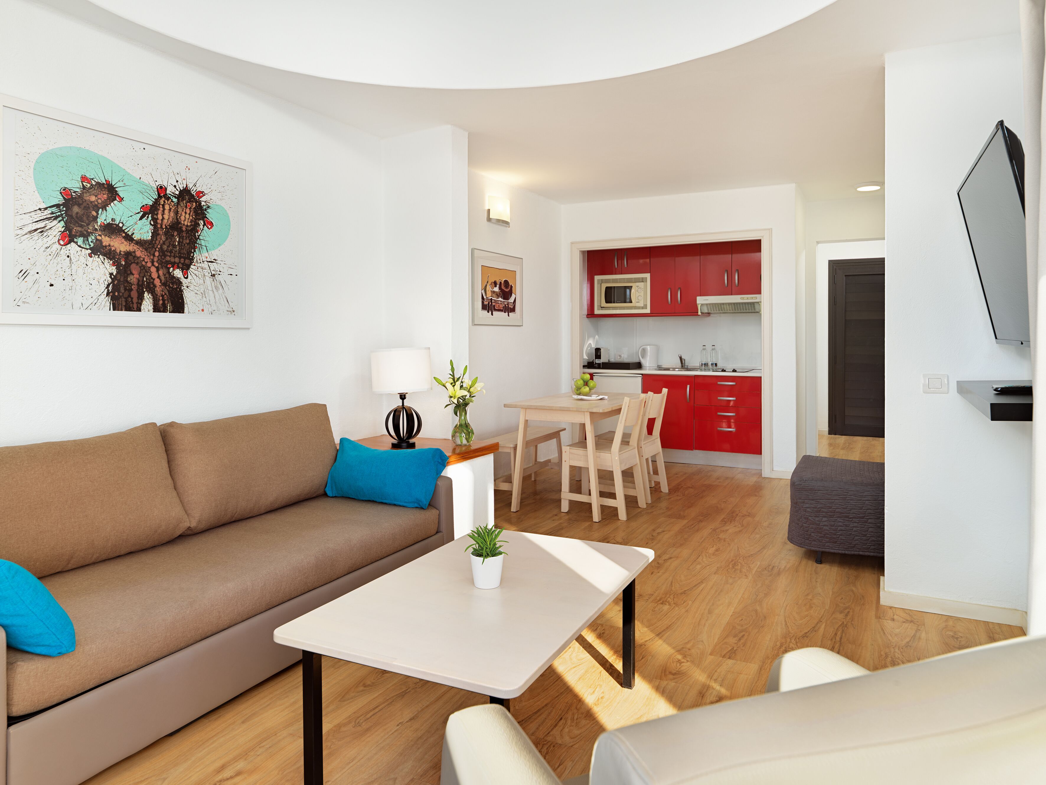 A modern living room with a brown sofa, a small table with a lamp, and a painting on the wall.