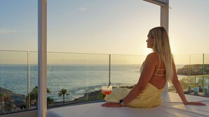 Una persona sentada en un balcón con vistas al océano.