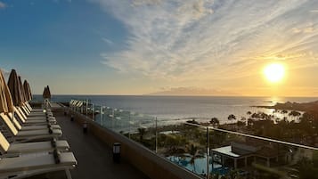 Enjoy ocean views from the balcony, featuring sun loungers and a poolside area with umbrellas.