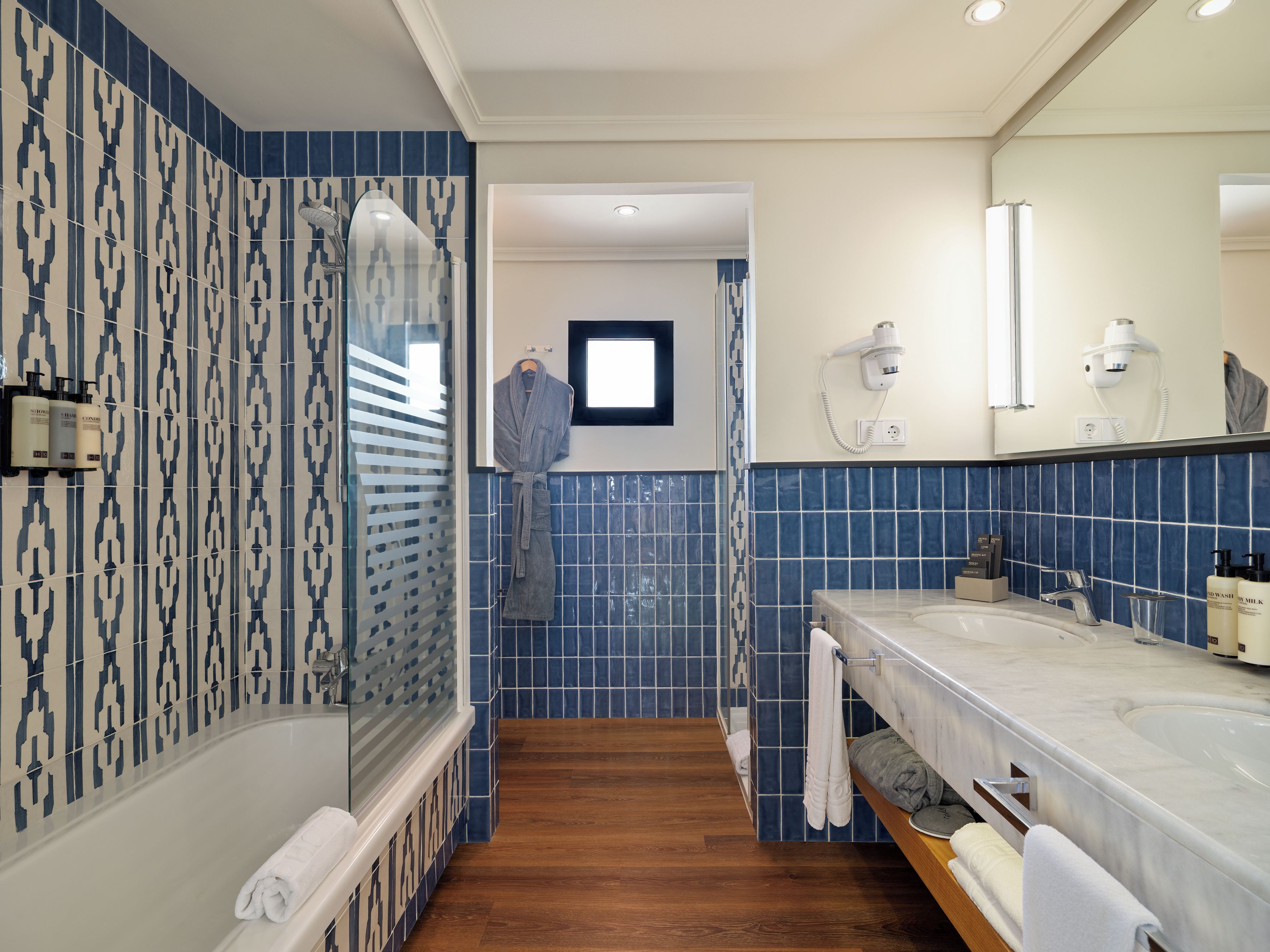 A bathroom with a bathtub, a shower, and a vanity with a mirror.